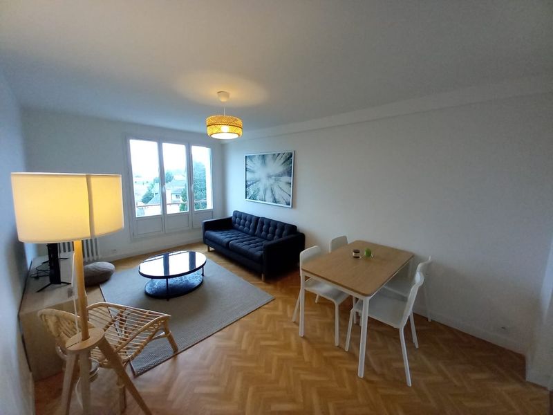 Séjour d'un appartement rénové, parquet et murs blancs
